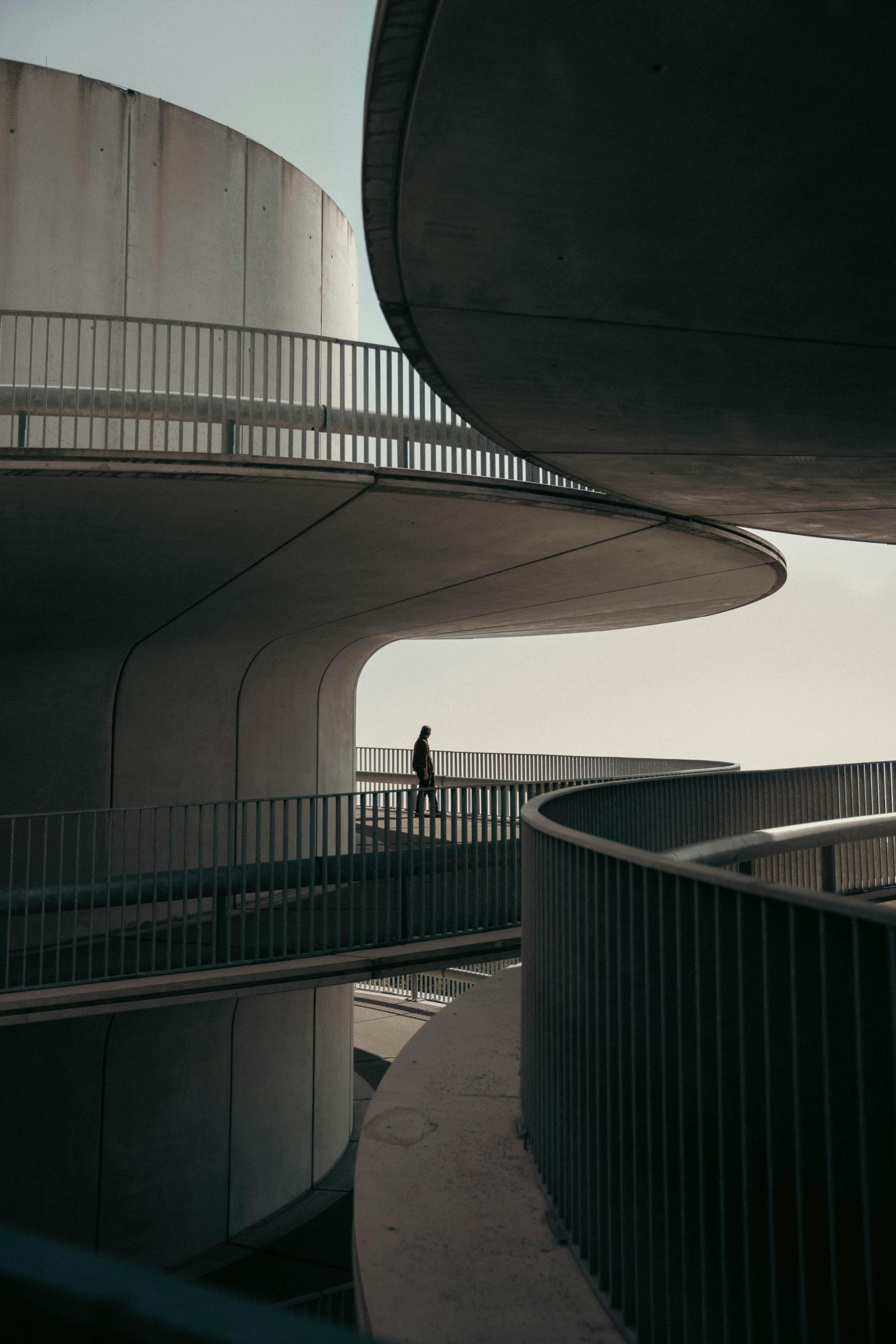 Silhouette of a person walking on a modern, curved architectural structure.